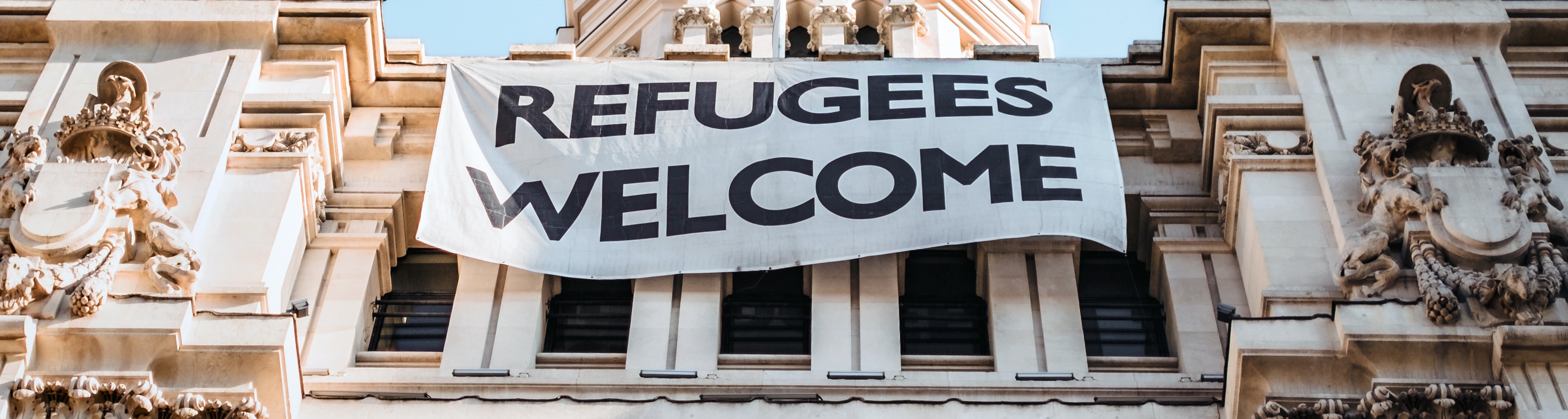 Image of building with sign saying Refugees Welcome